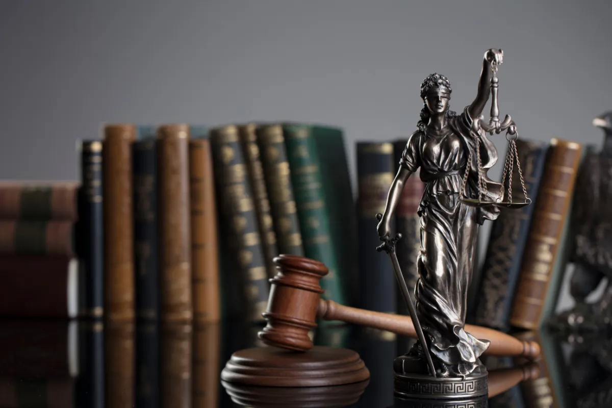Estatua de la justicia, mazo y libros jurídicos en un estudio de abogados